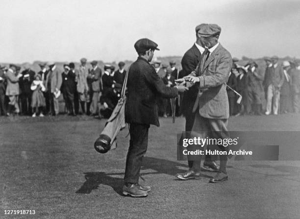 Scottish golfer Charles Macfarlane and English golfer Abe Mitchell with a young caddy, with spectators in the background, during the Annual...