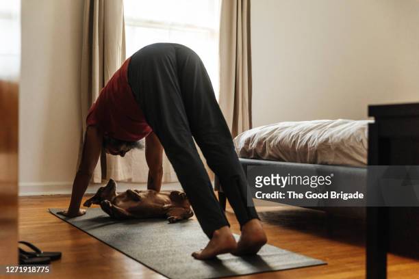 mature man practicing yoga in bedroom - man doing yoga in the morning stockfoto's en -beelden