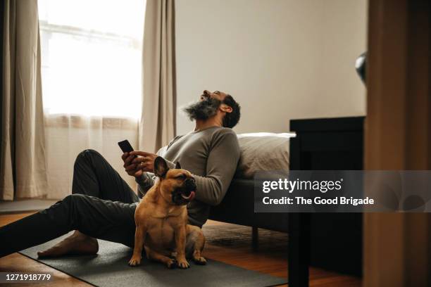 mature man laughing while using smart phone - middle age man with dog stock pictures, royalty-free photos & images