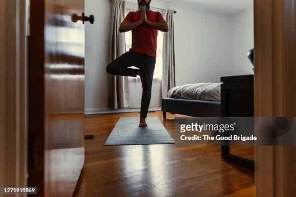 mature man practicing yoga in bedroom - standing on one leg fotografías e imágenes de stock