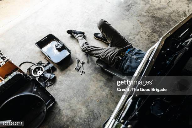 overhead view of man working on car in garage - autobergplaats stockfoto's en -beelden