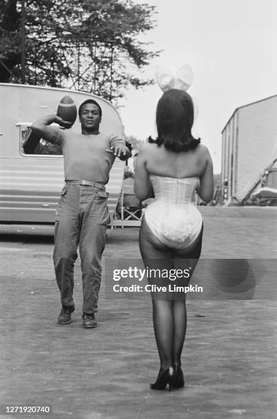 American football player and actor Jim Brown throws a ball for Bunny Girl Dolly Read on the set of the film 'The Dirty Dozen' at Elstree Studios, UK,...