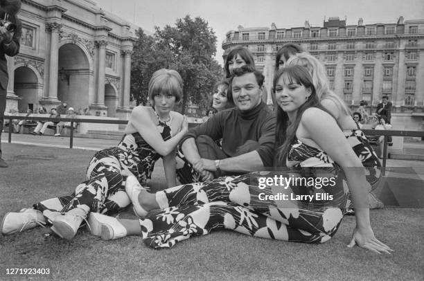 English pop singer Dickie Valentine posing at Marble Arch in London with the Beat Girls .