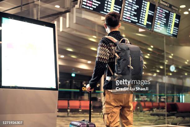 tourist  looking at the arrival departure board in airport terminal. - arrivals stock pictures, royalty-free photos & images