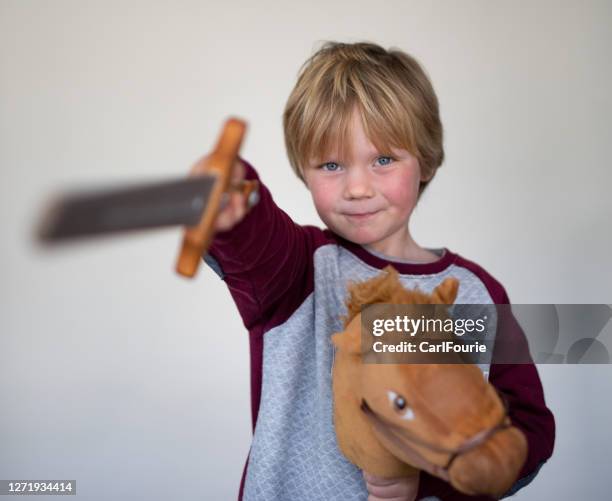 a young boy pose in front of a white screen while playing with a wooden sword. - knights of the round table arthurian legend stock pictures, royalty-free photos & images