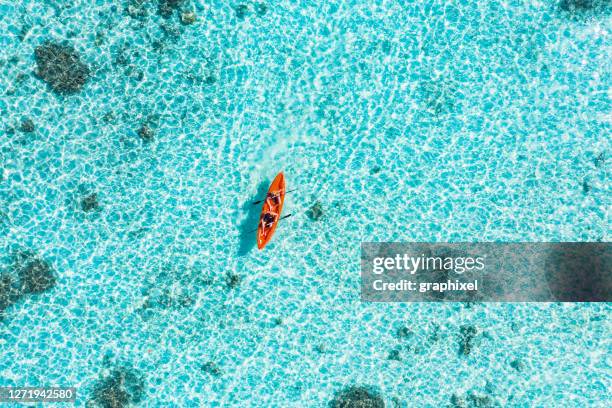 young couple paddling on glass bottom kayak in tropical ocean - kayaking aerial stock pictures, royalty-free photos & images