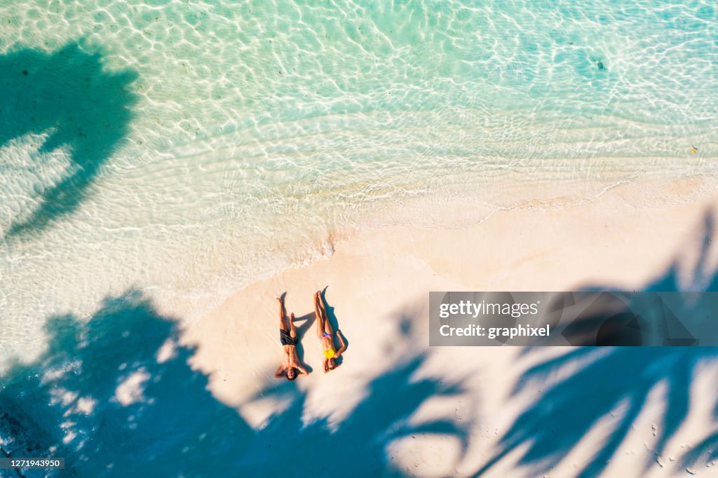 Pareja joven disfrutando del sol bajo las palmeras en Maldivas