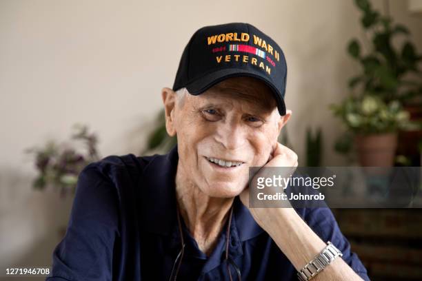 zweiter weltkrieg veteran lächelndkopf ruht auf der hand blick auf die kamera - veterans stock-fotos und bilder