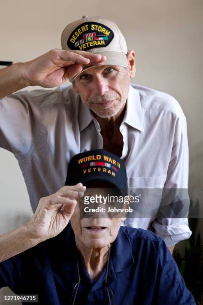 world war two veteran and son gulf war veteran at home saluting looking at camera - dementia father stock pictures, royalty-free photos & images