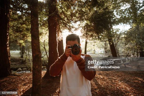 junger mann mit dslr-kamera - spiegelreflexkamera stock-fotos und bilder