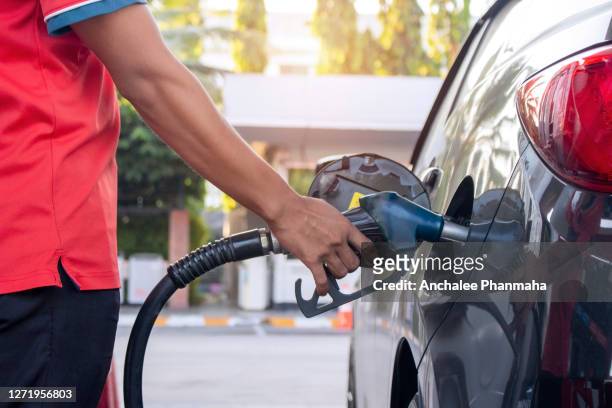 transportation concept;  hand hold fuel nozzle to add fuel i  the car at the gas station. close up of fuel monitoring system refueling petroleum to the vehicle at the gas station. - gas station ストックフォトと画像