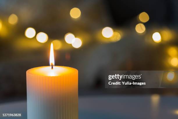 festive background with burning candle and bokeh - candle white background stock-fotos und bilder