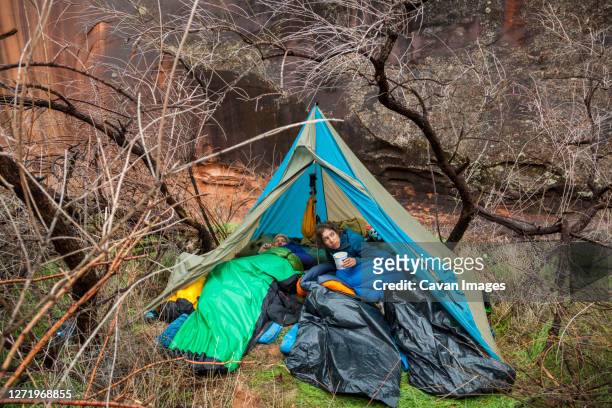 campers emerge from tent after rain near escalante river, utah - plane stock-fotos und bilder