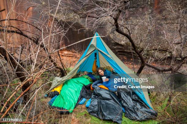 campers emerge from tent after rain near escalante river, utah - tarpaulin stock pictures, royalty-free photos & images