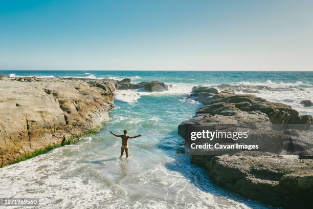 young man swimming in pacific ocean swimming hole in baja, mexico. - man skinny dipping stock pictures, royalty-free photos & images