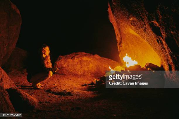 young woman in front of camp fire at night in northern california. - cave fire 個照片及圖片檔