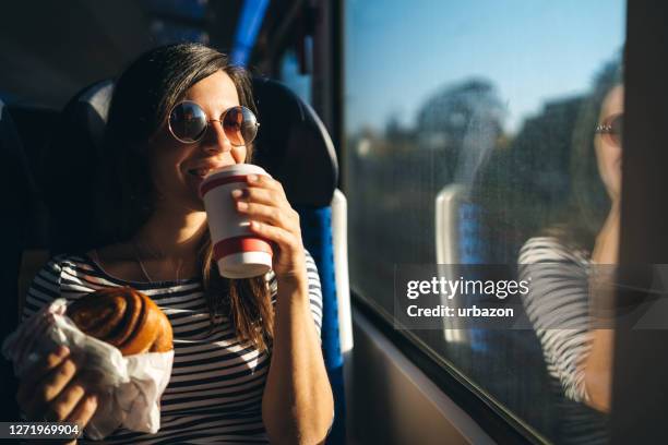 looking through window on a train ride - woman eating bagel stock pictures, royalty-free photos & images