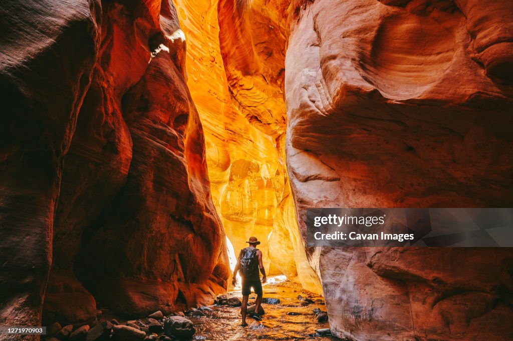 Young man wearing a hat, exploring a slot canyon in Kanarra Fall, Utah