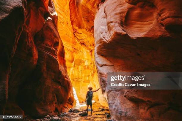 young man wearing a hat, exploring a slot canyon in kanarra fall, utah - pothole photos et images de collection