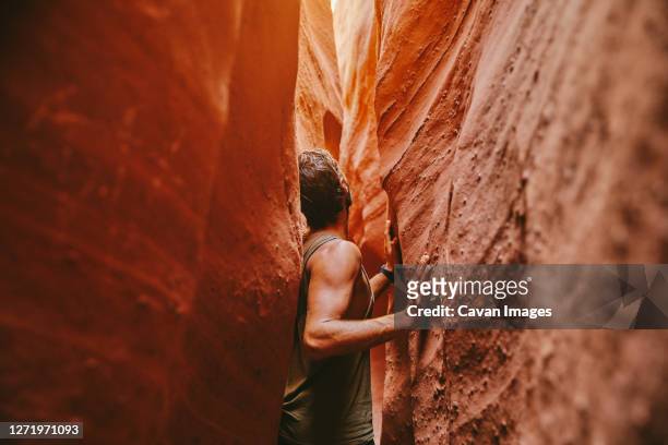 young man exploring narrow slot canyons in escalante, during summer - narrow stockfoto's en -beelden