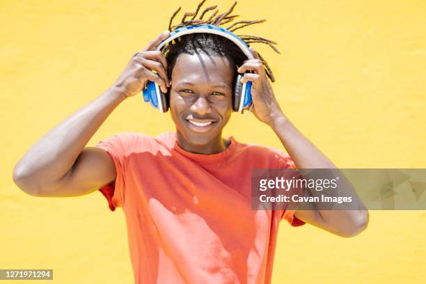 cheerful black guy putting on headphones - adolescent africain stock pictures, royalty-free photos & images