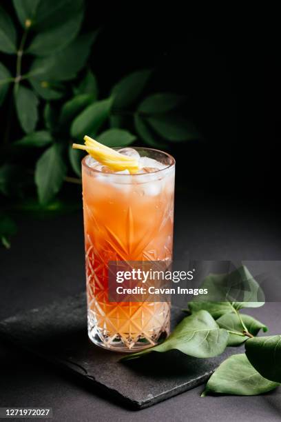 glass of alcoholic coctail with ice on black background - mai tai stock-fotos und bilder