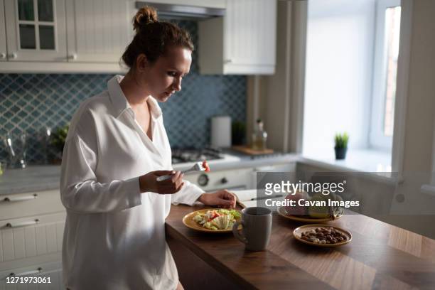businesswoman having breakfast at home - donna piatto foto e immagini stock
