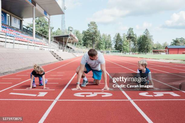 father and his kids getting ready to run on a track to race - kids track and field stock pictures, royalty-free photos & images