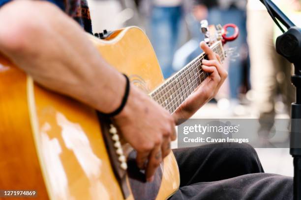 selective focus on the hands of a young man playing a guitar in a crowded street - scène de vie ville photos et images de collection