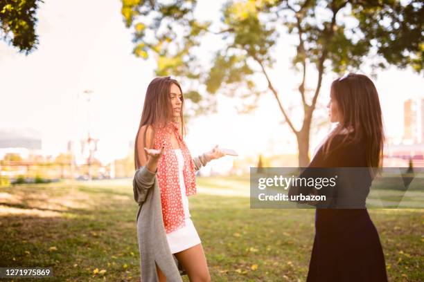 women arguing in a public park - sibling argument stock pictures, royalty-free photos & images