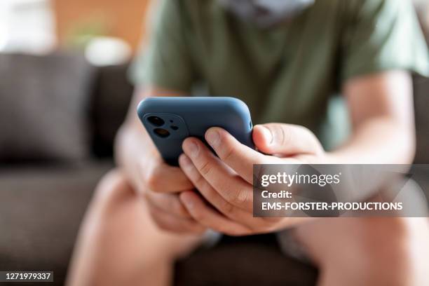 teenager boy is using smartphone at home - home schooling - bambini maschi foto e immagini stock