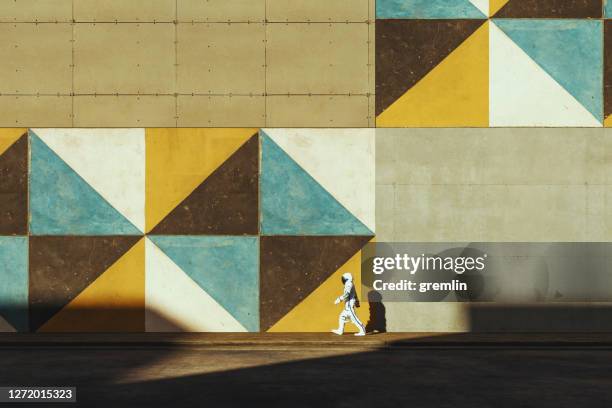 astronauta che cammina per strada - murale foto e immagini stock