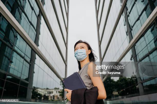 asian chinese businesswoman with face mask holding digital tablet in business district - businesswoman mask stock pictures, royalty-free photos & images