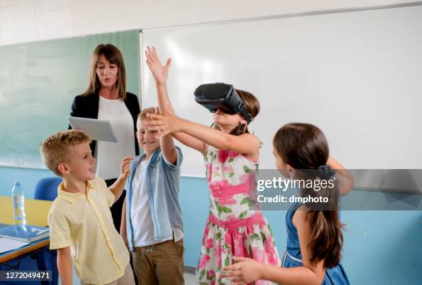 schoolchildren playing with virtual head seat in classroom - virtual reality classroom stock pictures, royalty-free photos & images