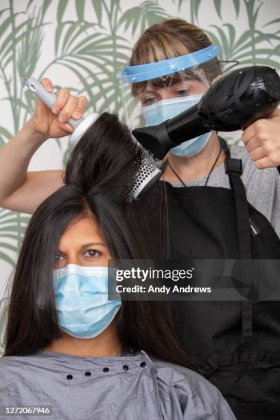 hairdresser blow drying customer's hair during covid-19 - lockdown haircut stock pictures, royalty-free photos & images