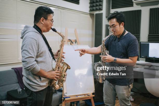 asian chinese mid adult man learning music instrument playing saxophone from his instructor in music studio stock photo... - saxophone stock pictures, royalty-free photos & images