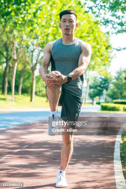 young man stretching in the park - touching toes stock pictures, royalty-free photos & images