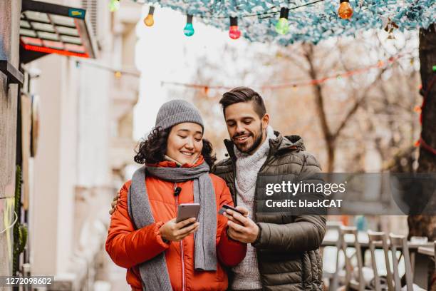 young couple shopping online outdoors - holiday shopping stock pictures, royalty-free photos & images