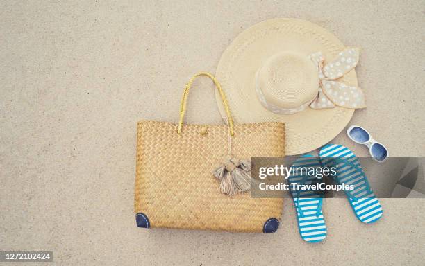 beach accessories. straw hat. bag. sun glasses and flip flops on a tropical beach. fun holiday travel on sandy beach. summertime. summer vibes. - beach bag stockfoto's en -beelden