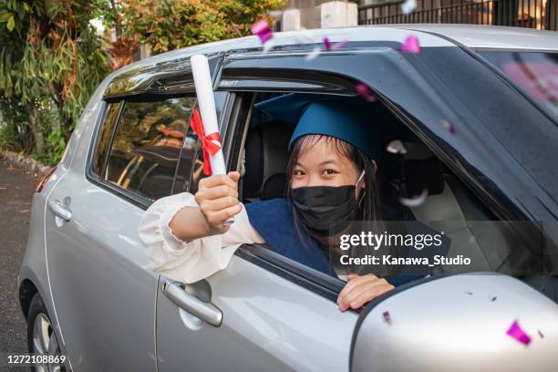 happy east asian graduate showing her rolled up certificate - car parade stock pictures, royalty-free photos & images