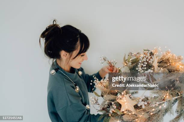 young woman decorating her living room for the upcoming holidays - messy hair bun stock pictures, royalty-free photos & images