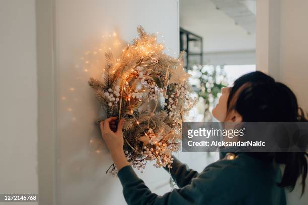 young woman decorating her living room for the upcoming holidays - decoration stock pictures, royalty-free photos & images