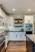 Floating shelves between white cabinetry in kitchen