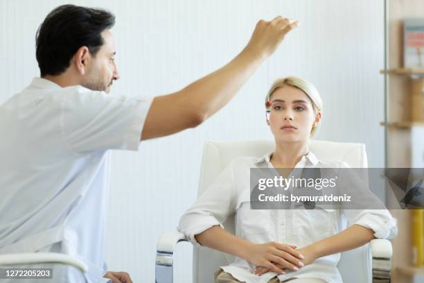mannelijke therapeut die hypnosetherapie op jonge vrouw gebruikt - hypnose stockfoto's en -beelden