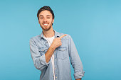 Look at ads here! Portrait of handsome happy man in stylish denim shirt pointing aside, showing copy space