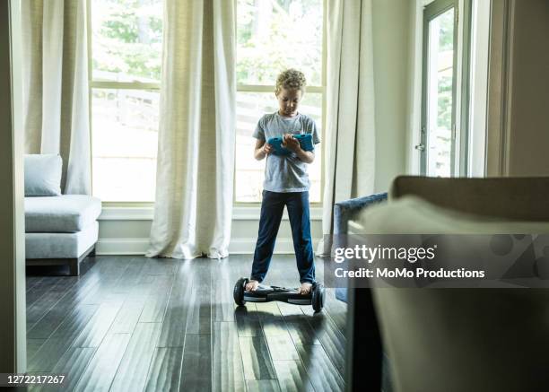 young boy using digital tablet while riding hoverboard - hoverboard - fotografias e filmes do acervo