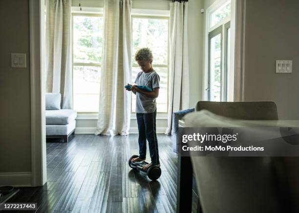 young boy using digital tablet while riding hoverboard - hover board ストックフォトと画像