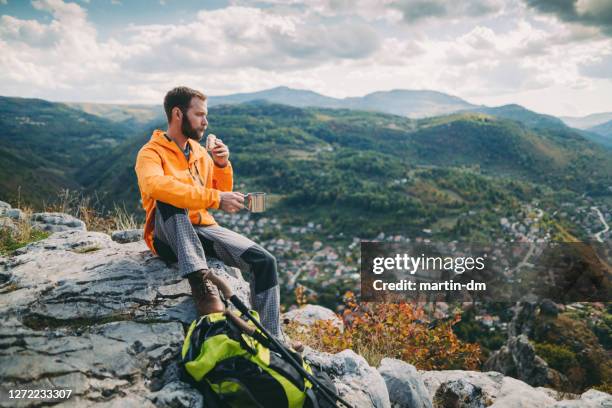 tourist eating sandwich with cup of tea in the mountain - outdoor guy sitting on a rock stock pictures, royalty-free photos & images