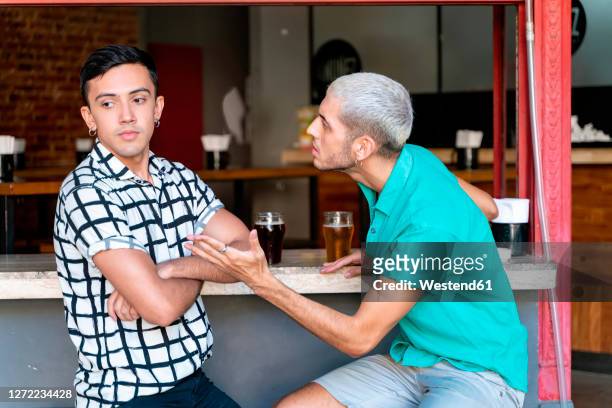 gay couple arguing while sitting at bar counter - friends argue fotografías e imágenes de stock