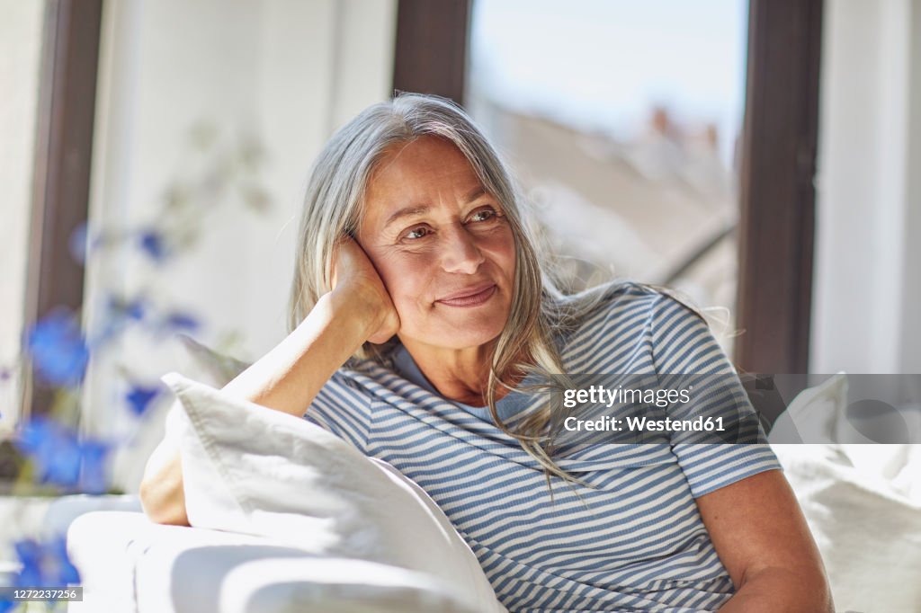 Smiling woman relaxing on sofa in living room